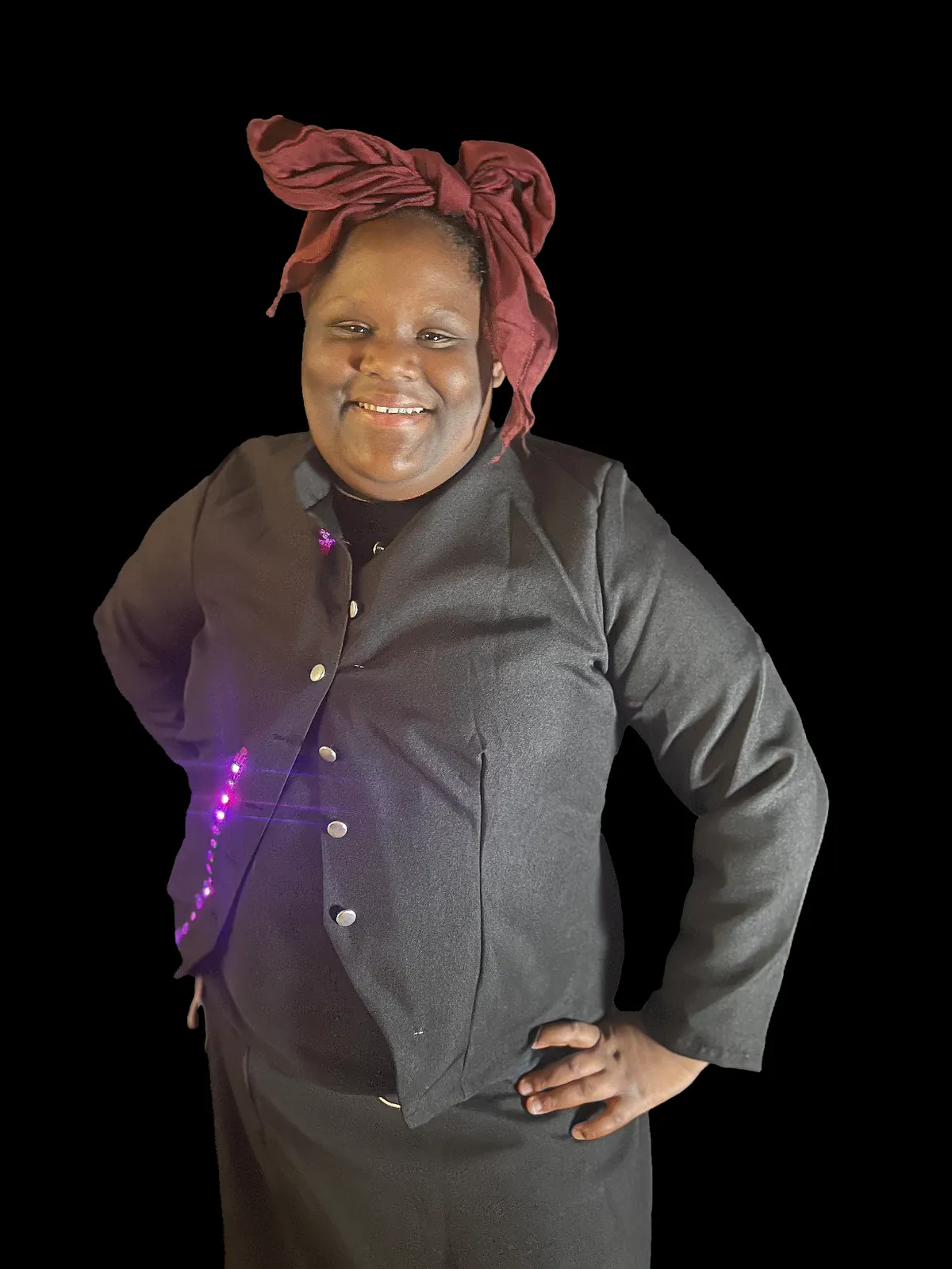 Student as Harriet Tubman in a dark buttoned jacket and a deep red headwrap, a line of purple LEDs glowing down the front