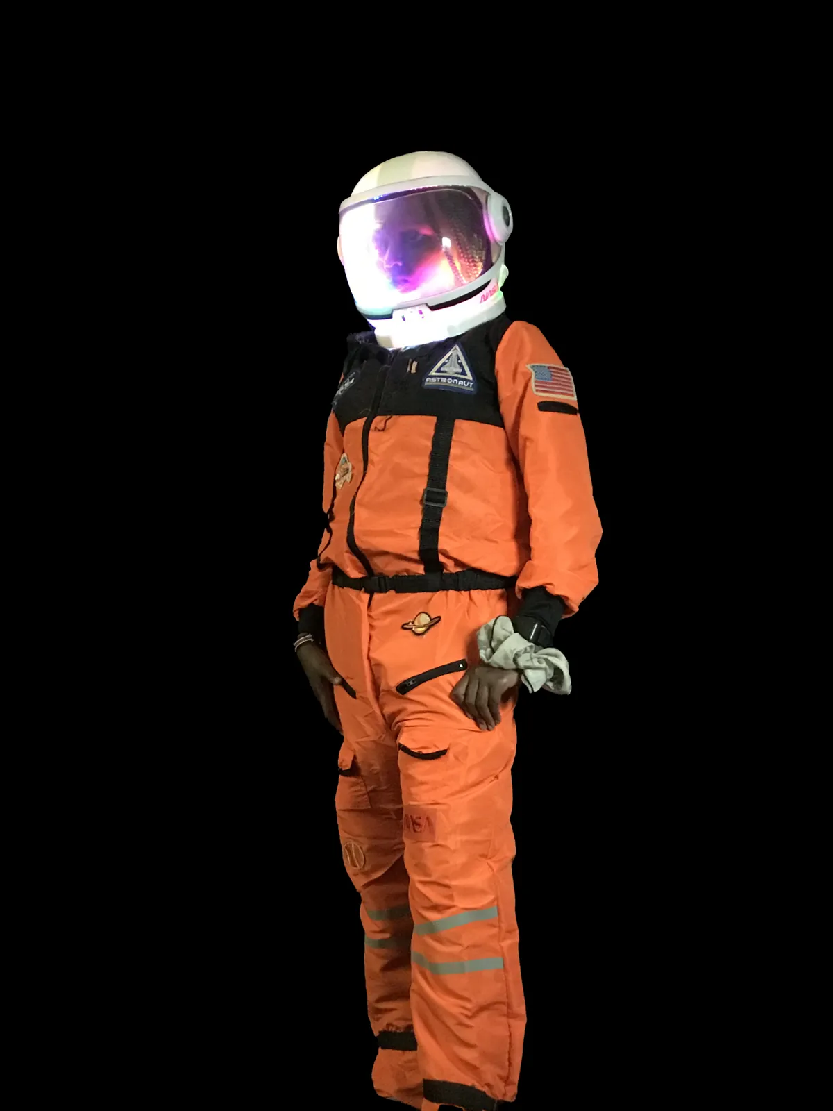 Student as Mae Jemison in an orange astronaut suit with a helmet lit from inside by colored LEDs