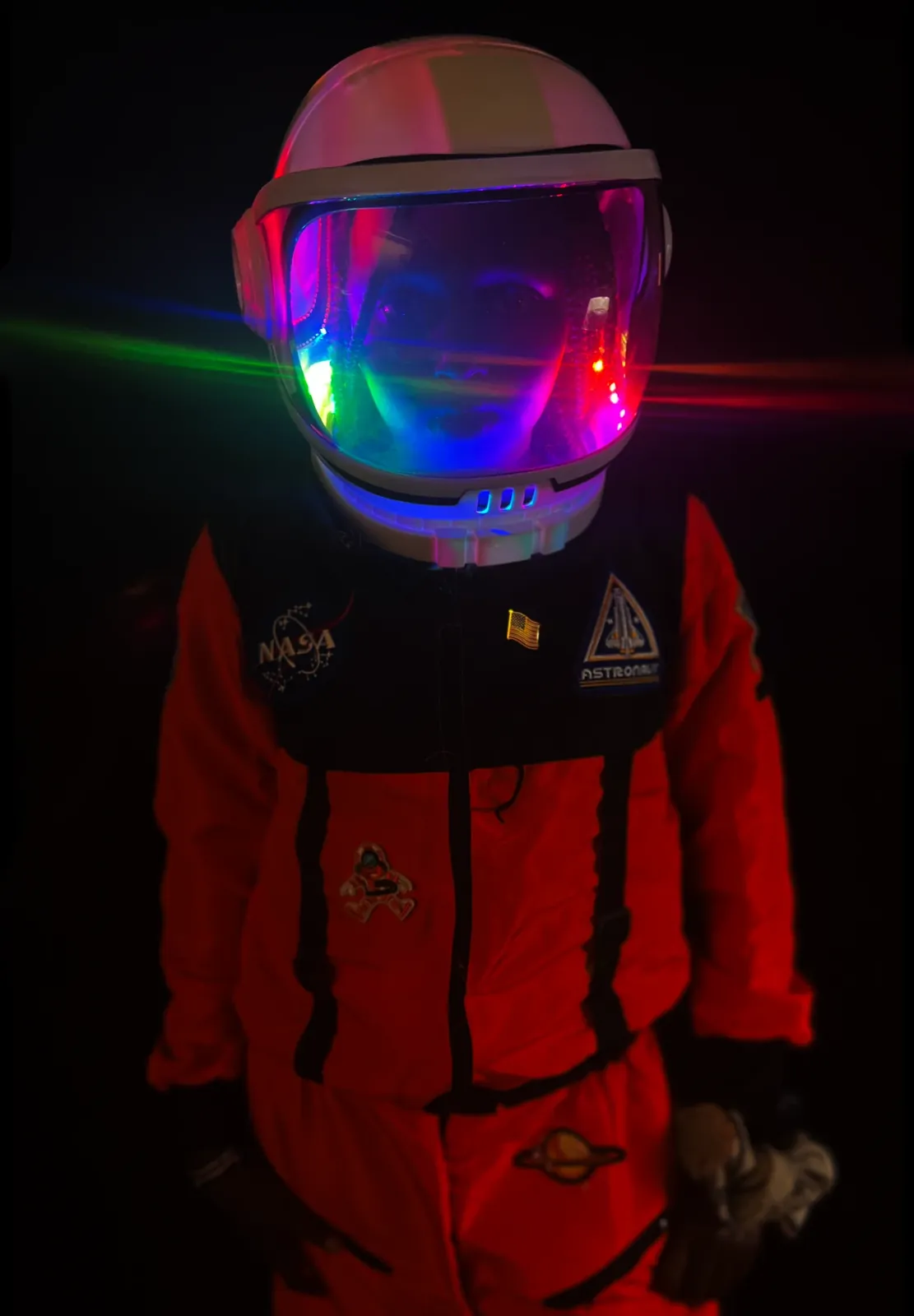 Close-up of a student as Mae Jemison in an orange NASA suit, rainbow LEDs glowing inside the helmet visor
