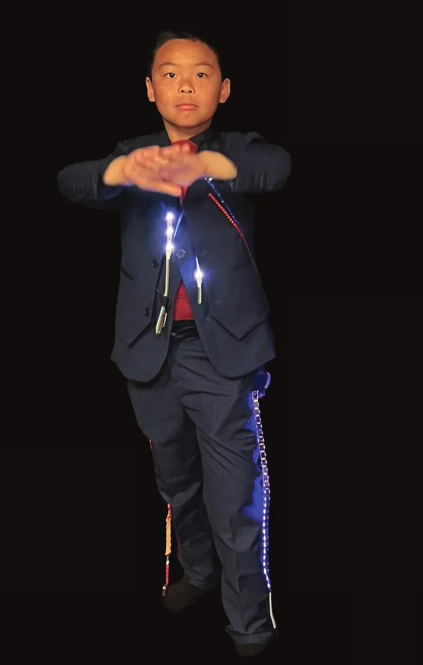Student as Barack Obama in a dark suit, hands together, LEDs glowing along the jacket