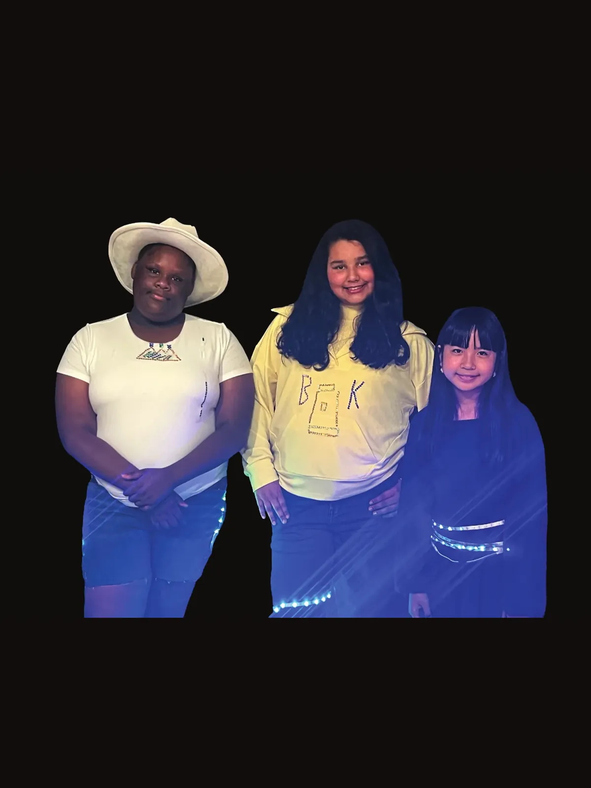 Three students for Beyoncé: one in a cowboy hat and white top, one in a yellow sweatshirt, one in blue with LED trim