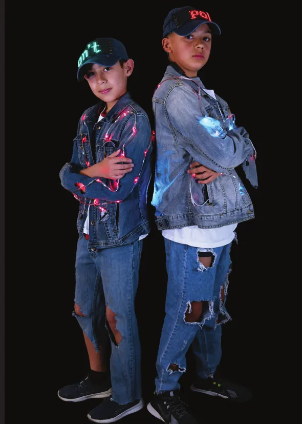 Denim Pollution: two students in ripped jeans and denim jackets lined with lights, one in a cap with a scrolling LED message