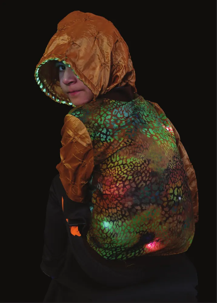 Desert Dweller: student in a hooded jacket with a lizard-scale pattern glowing green and orange