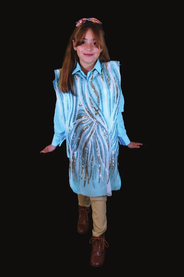 Mangrove: student in a long pale blue coat embroidered with flowing root lines