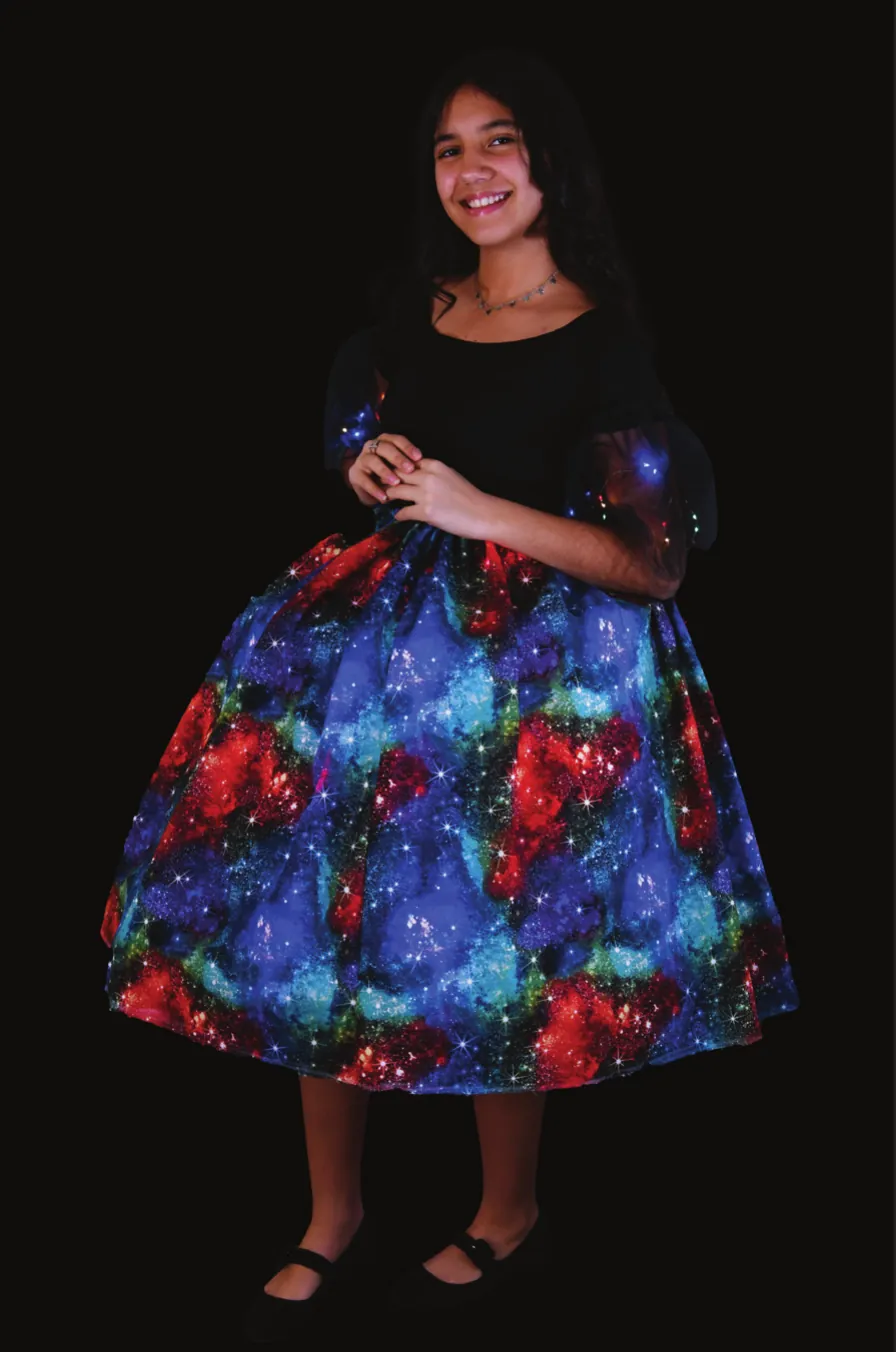 Queen of the Cosmos: student in a full hoop skirt of galaxy-print fabric with a black top, fairy lights glowing in the skirt
