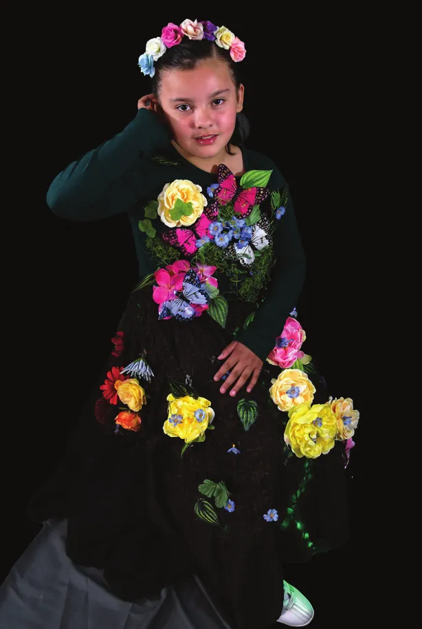 Mother Earth: student in a black gown scattered with bright flowers and a flower crown