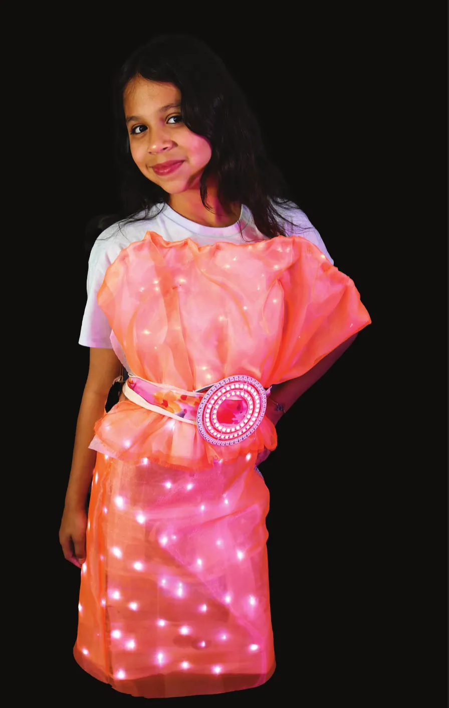 Sunshine, Sunbright: student in a coral dress glowing with white lights and a round sun at the waist