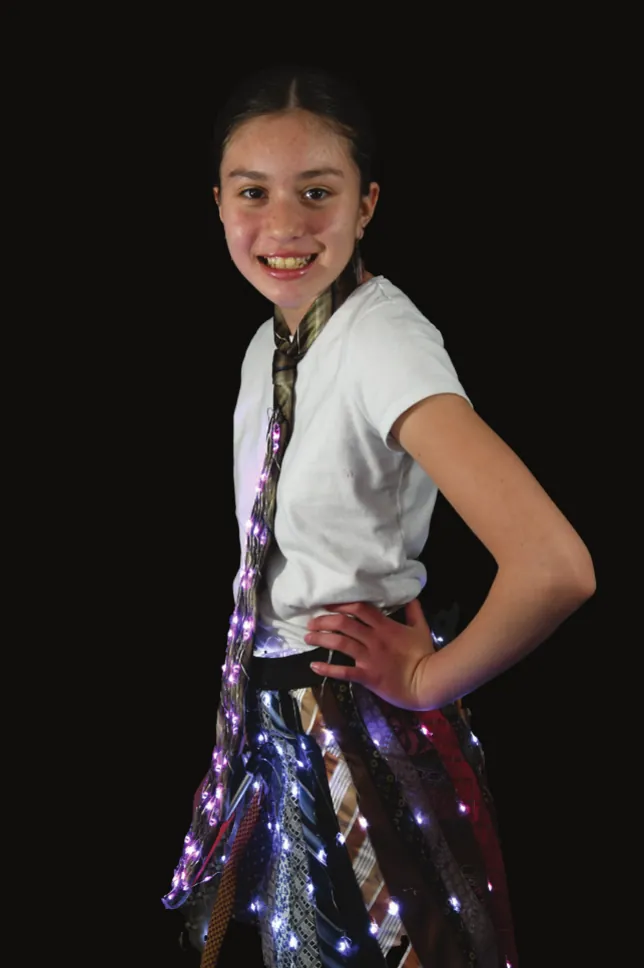 Tied Up-Cycle: student in a white T-shirt and a skirt made of upcycled neckties threaded with lights